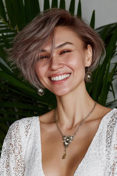 Een vrouw met kort, asymmetrisch kapsel met zijscheiding en licht golvend haar dat volume heeft aan één kant.