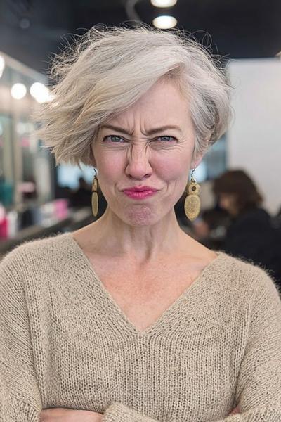 Een oudere dame met een modieus, kort asymmetrisch kapsel met golvend grijs haar.