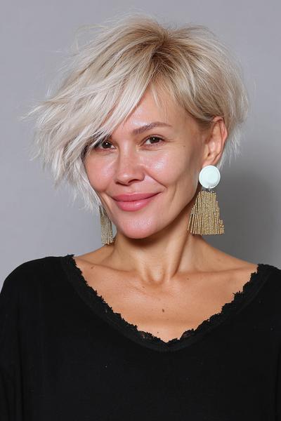 Een vrouw met kort, asymmetrisch blond haar dat speels in lagen is geknipt.