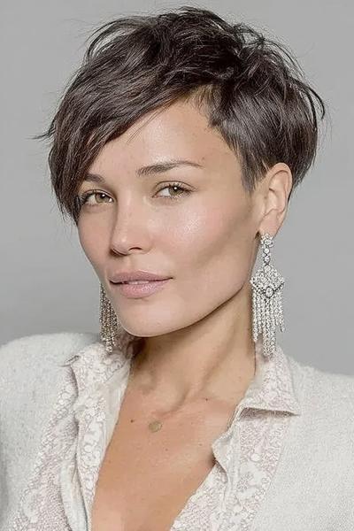Een vrouw met een vlot, kort kapsel met een asymmetrische zijscheiding en speelse, gelaagde lokken.