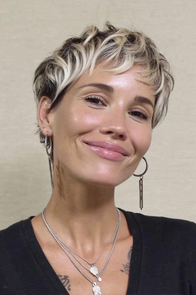 Een vrouw met een kort kapsel met golvende lagen en lichtblonde highlights bovenop.
