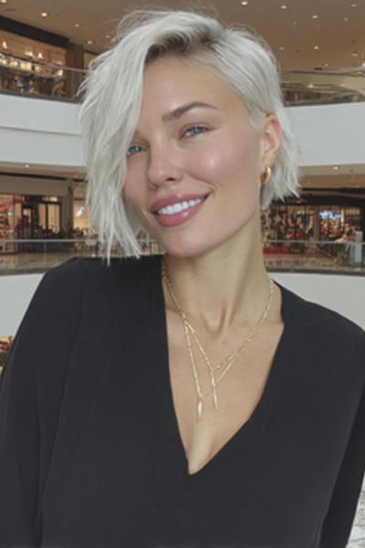 Een vrouw met een kort, asymmetrisch kapsel en platinablond haar dat losjes in lagen is gestyled.