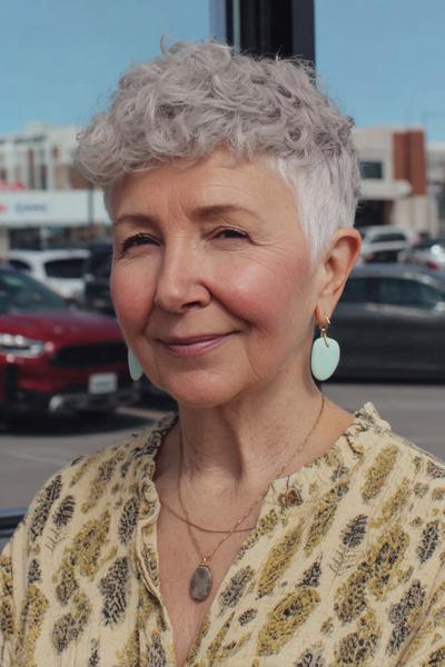 Een vrouw met kort, golvend grijs haar in een vlotte, moderne pixie cut.
