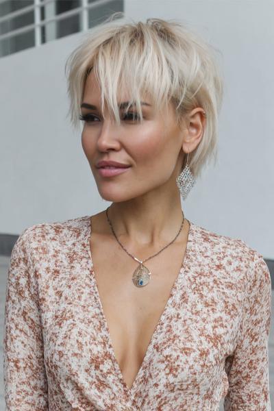Een vrouw met een vlot, kort kapsel met platinablond haar en speelse, warrige lokken aan de voorkant.
