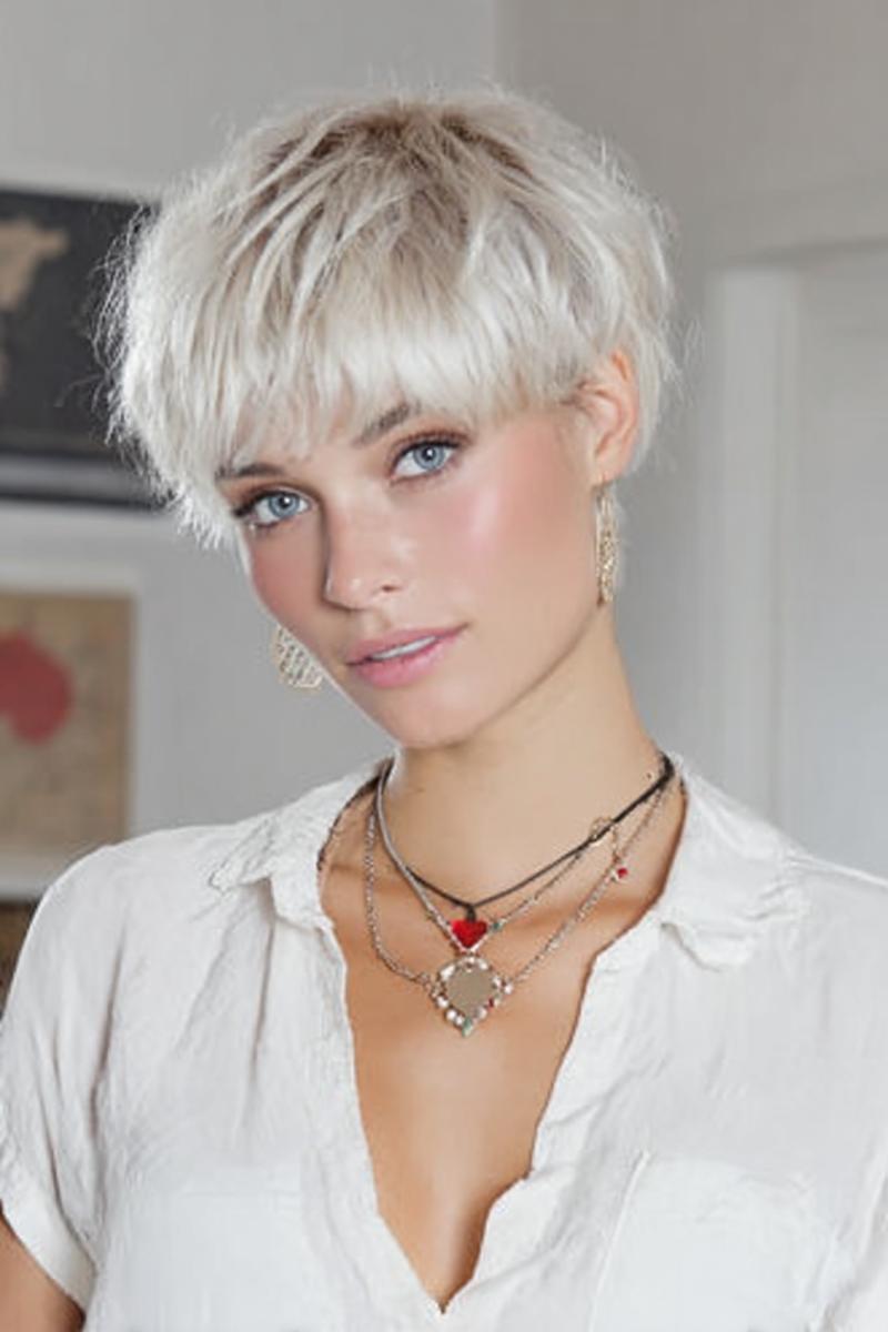 Een vrouw met een kort, geplatineerd blond kapsel met een volle pony en warrige textuur.