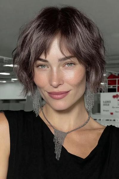 Een vrouw met kort, golvend haar in een nonchalante bob-lijn en een zijwaartse pony.