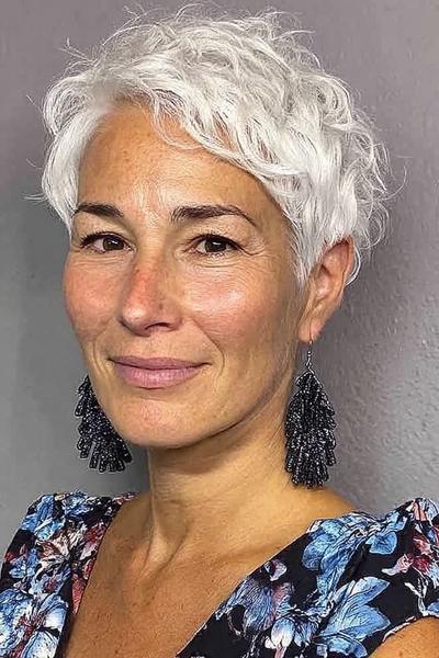 Vlotte korte kapsel voor vrouwen van 60 plus met golvend, wit haar en een zijscheiding.