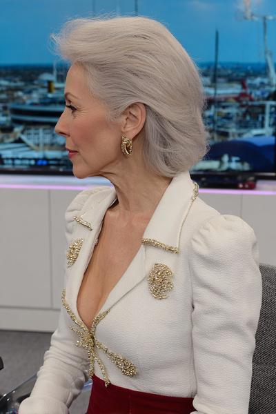 Een oudere dame met een stijlvolle, kinlange grijze bobkapsel dat elegant naar achteren is gestyled.