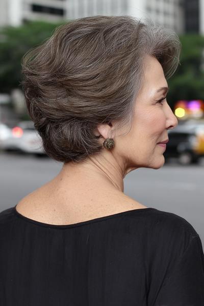 Een oudere dame met kort, volumineus grijs haar dat in zachte lagen is gestyled.