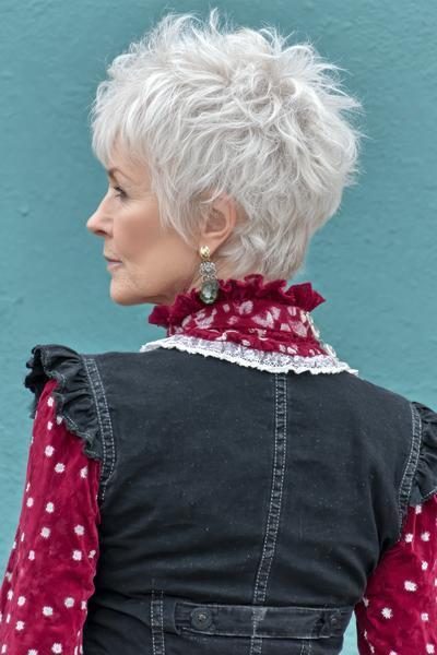 Een oudere dame met kort, wit haar in een vlotte, gelaagde en warrige coupe.