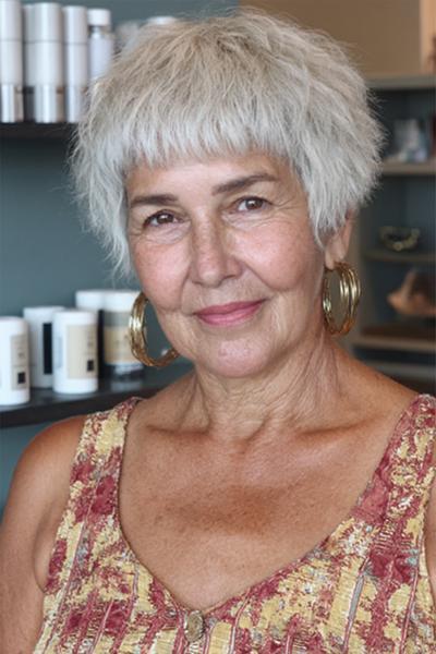 Een vrouw met kort, grijs haar in een vlotte, gelaagde pixie coupe met pony.