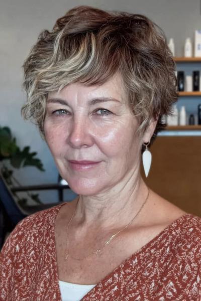 Een vlotte, korte kapsel voor vrouwen van 60-plus met golvend haar en lichte highlights aan de voorkant.