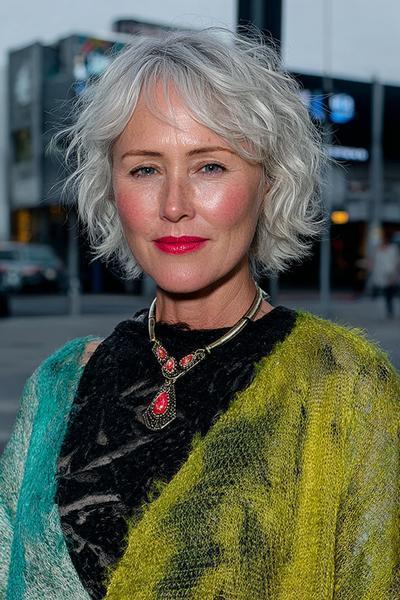 Een oudere dame met een kort, golvend grijs bobkapsel en een zijwaartse pony.