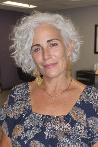 Een vrouw met kort, golvend grijs haar in een vlot en modern kapsel, geschikt voor dames van 60 jaar en ouder.