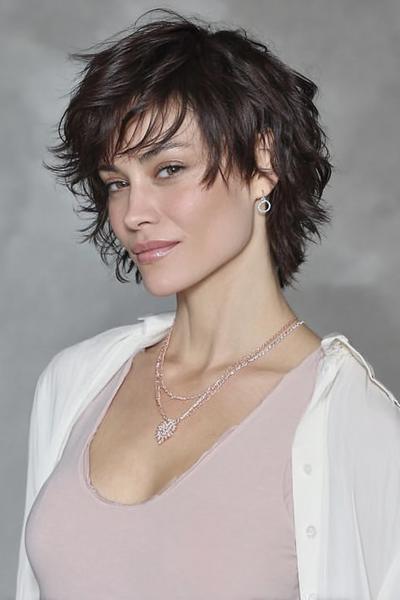 Een vrouw met een vlot, kort kapsel met warrige, gelaagde lokken en pony, gestyled in een nonchalante look.