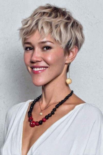 Een vrouw met een kort, golvend en warrig kapsel in een blonde kleur.