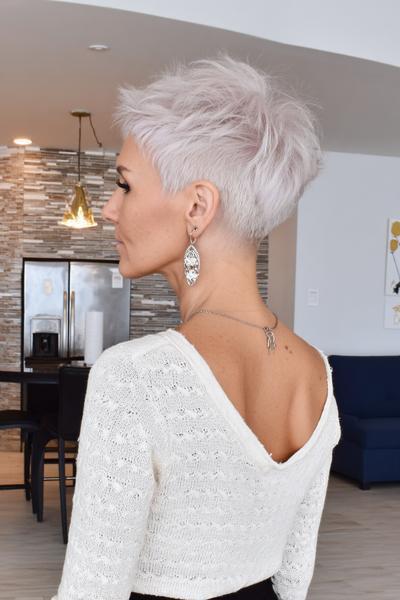 Een vrouw met een stijlvol, kort kapsel met een asymmetrische snit en lichtblond haar.