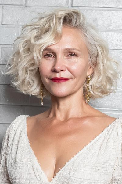 Een oudere dame met een kort, golvend bobkapsel en zilvergrijs haar.