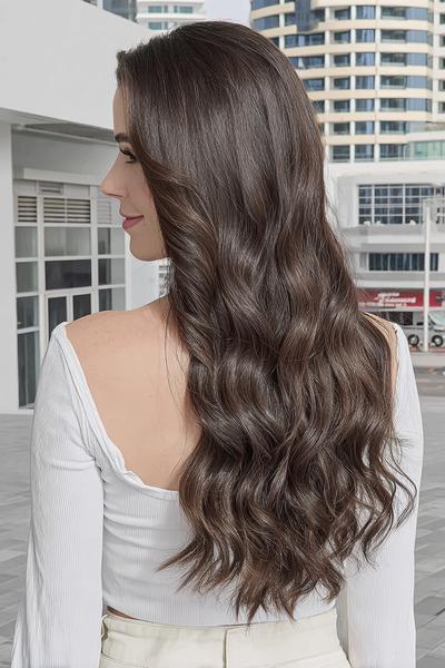 Een vrouw met lang, golvend bruin haar dat los over haar rug valt, gefotografeerd van achteren.