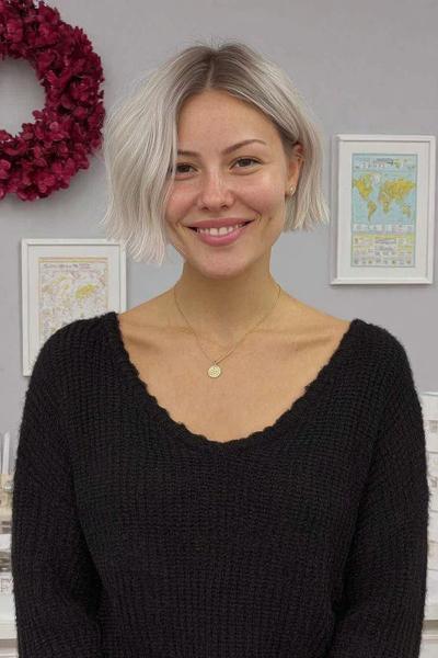 Een vrouw met een kort, golvend blond kapsel met een midden scheiding.