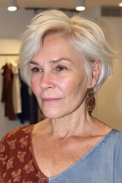 Een vrouw met kort, stijlvol, wit haar in een vlotte, gelaagde boblijn kapsel.