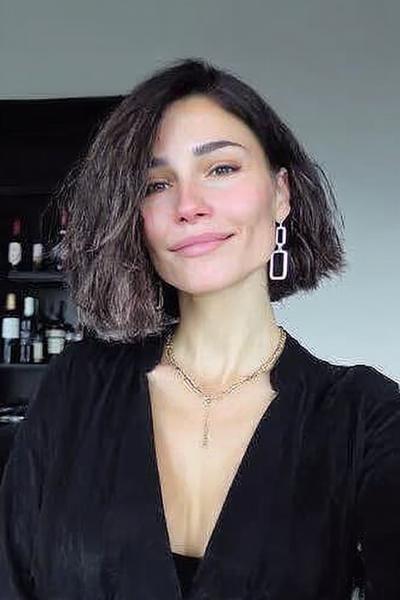 Vrouw met een kinlange, asymmetrische bob met zijscheiding en licht golvend haar.