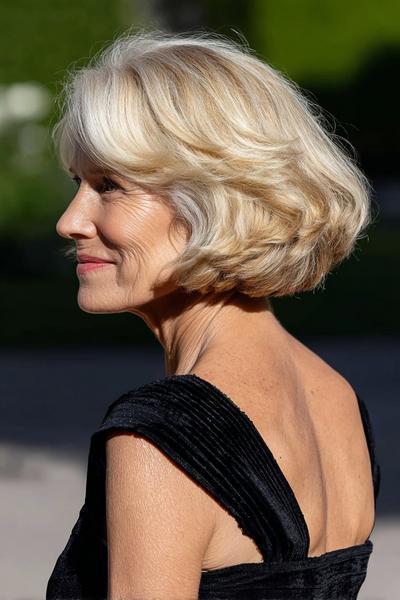 Een oudere dame met een chique, golvende blonde boblijn en zijwaartse pony.