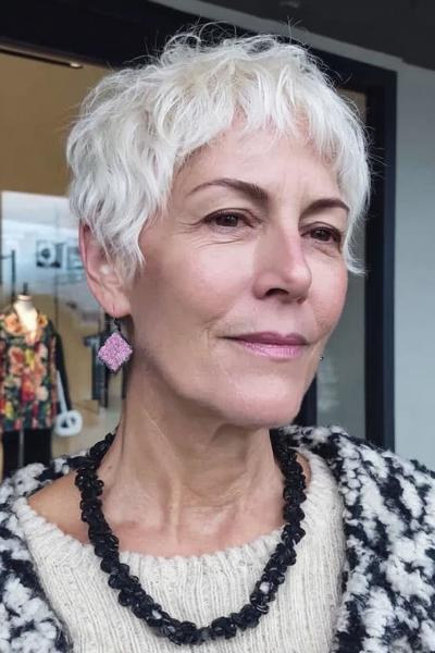 Een vrouw met kort, golvend, wit haar en een luchtig, vlot kapsel geschikt voor dames van 60 plus.
