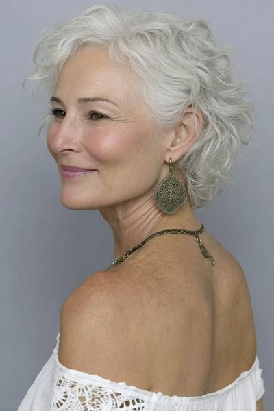 Een oudere dame met kort, golvend wit haar in een vlot en modern kapsel.