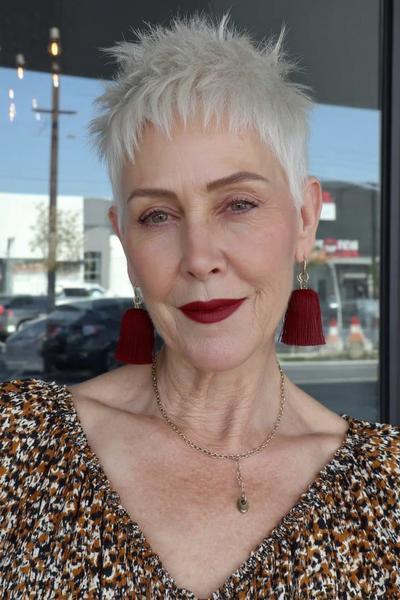 Een vlotte, korte, modern gesneden pixie-kapsel met speelse, piekerige lokken en zilverwit haar, gedragen door een vrouw van boven de 60.