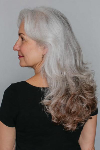Een oudere dame met lang, golvend grijs haar dat zacht over haar schouders valt.