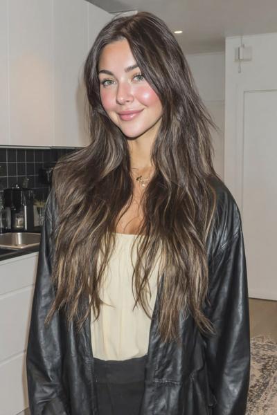 Een vrouw met lang, golvend bruin haar dat los over haar schouders valt.