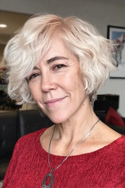 Een vrouw met een vlot, kort kapsel met golvende, lichtblonde haren en een zijscheiding.