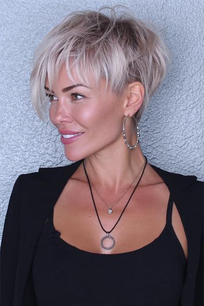 Een vrouw met een kort, gelaagd kapsel met blonde highlights en een speelse zijscheiding.