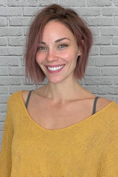 Een vrouw met een kort, warrig bobkapsel en licht golvend haar dat zijwaarts is gestyled.