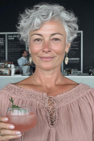 Een vrouw met kort, golvend grijs haar in een vlotte en moderne coupe.