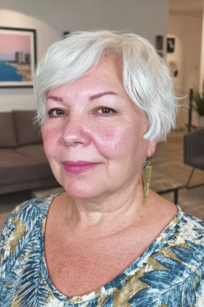 Een vrouw met kort, golvend, witgrijs haar in een vlot en modern kapsel.