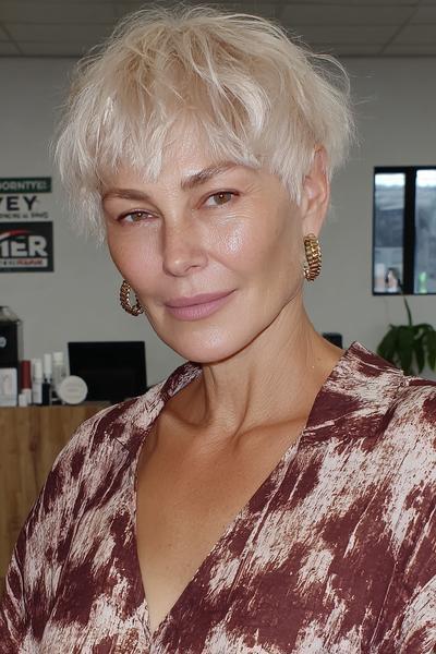Een vrouw met kort, golvend, lichtblond haar in een vlot en modern kapsel geschikt voor dames van 60 plus.