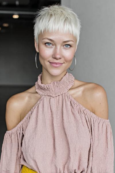 Een vrouw met een kort, blond pixiekapsel en rechte pony.