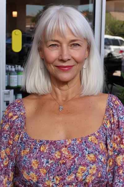 Een oudere dame met recht, schouderlang wit haar en een pony, gestyled in een bob kapsel.