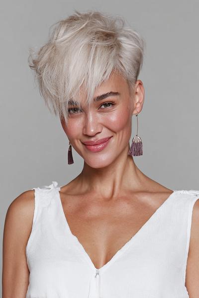 Een vrouw met een kort, asymmetrisch blond kapsel met lange lokken aan de voorkant en kortere zijkanten.