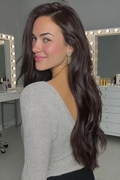 Een vrouw met lang, golvend donkerbruin haar dat los over haar schouders valt.