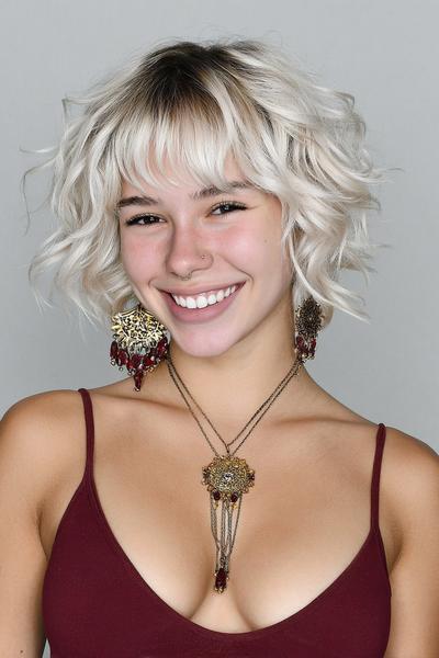 Een vrouw met een vlot, kort kapsel met golvende, lichtblonde lokken en korte pony.