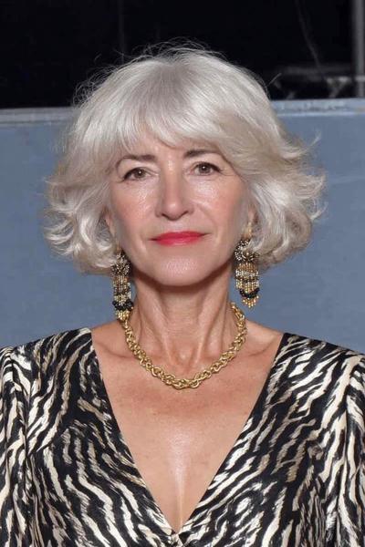 Een oudere dame met een kort, golvend bob kapsel in zilvergrijs haar.