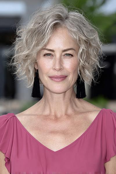 Een vrouw met kort, grijs, golvend haar in een vlotte en moderne coupe.