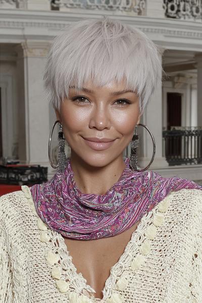 Een vrouw met een vlot, kort kapsel met een platinum blonde kleur en pony, gestyled in een speelse, warrige look.