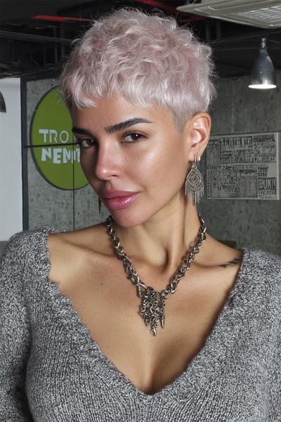 Een vrouw met een trendy, kort geknipt kapsel met lichte, golvende platinablonde lokken.