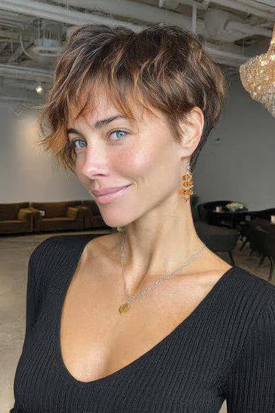 Een vrouw met kort, golvend haar in een speelse pixie cut met licht bruine en blonde highlights.