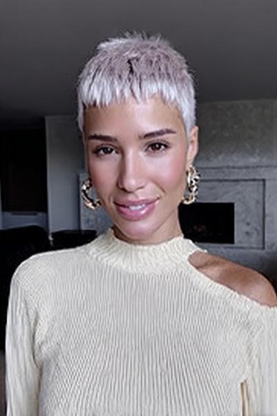 Een vrouw met kort, lichtblond haar in een moderne pixie cut met rechte pony.