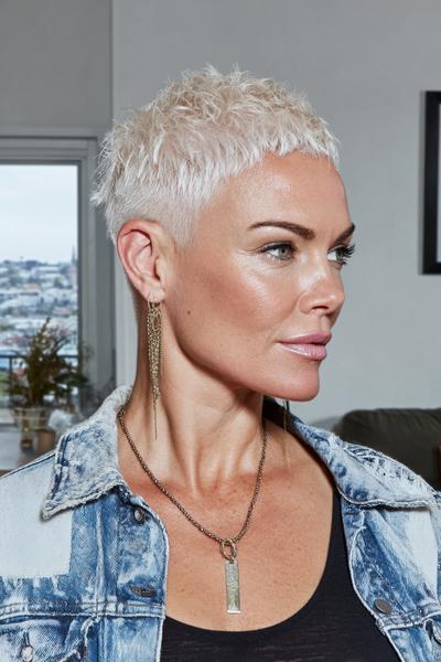Een vrouw met een trendy, kort, blond kapsel met een warrige textuur en opgeschoren zijkanten.